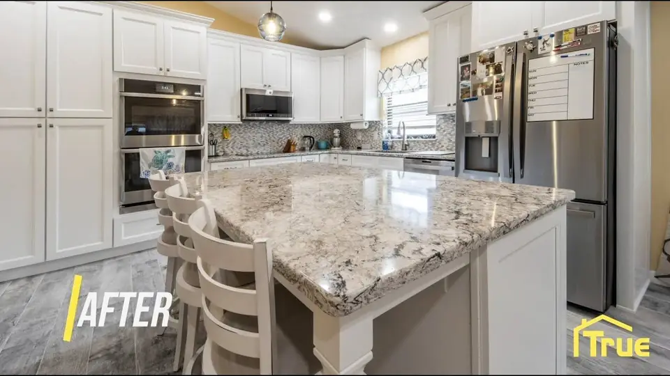 Kitchen with new white cabinets and a granite island replacing builder-grade finishes, by True Builders
