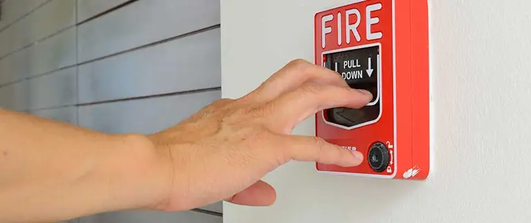 Hand activating a red fire alarm during emergency response at Central Florida business