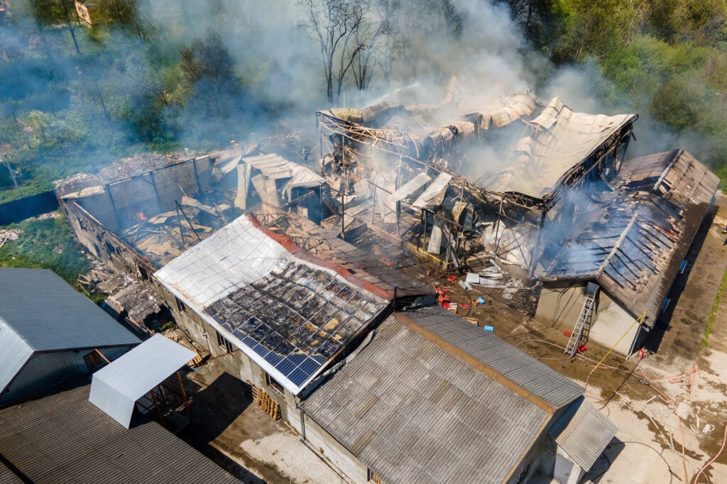 Aerial view of a fire-damaged building in Central Florida with collapsed roof and active smoke.