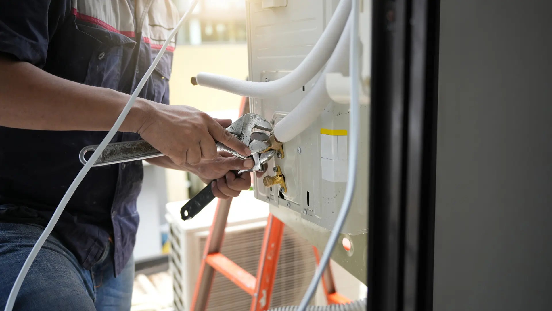 Technician using wrench to fix water leak in aircon condensate drain line in Lakeland Florida